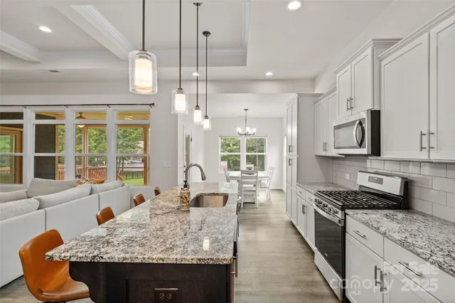 a large kitchen with stainless steel appliances granite countertop a stove and a sink