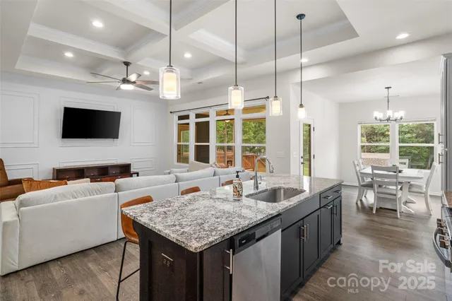a kitchen with granite countertop a sink a counter top space and living room view