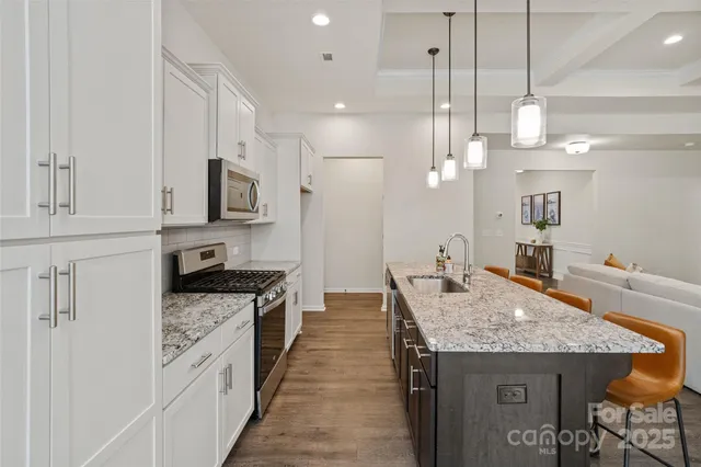 a kitchen with kitchen island granite countertop a stove a sink dishwasher and a refrigerator with wooden floor