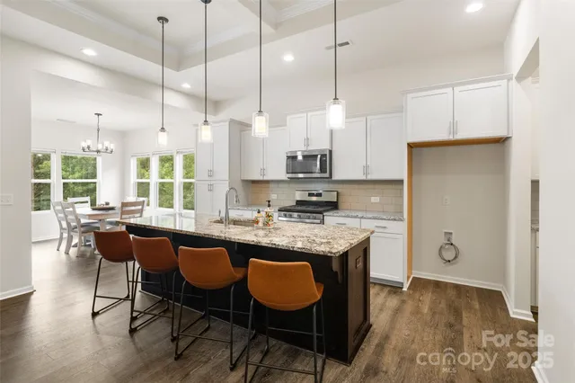 a kitchen with granite countertop a table chairs a sink dishwasher refrigerator and cabinets