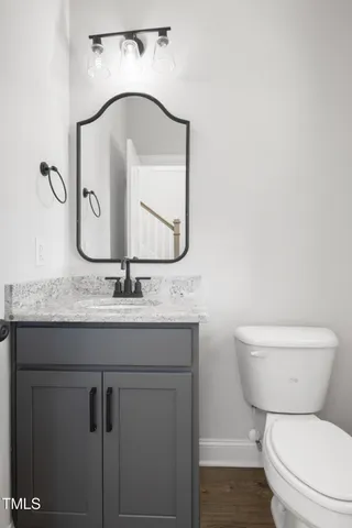 a bathroom with a granite countertop sink a toilet and a mirror