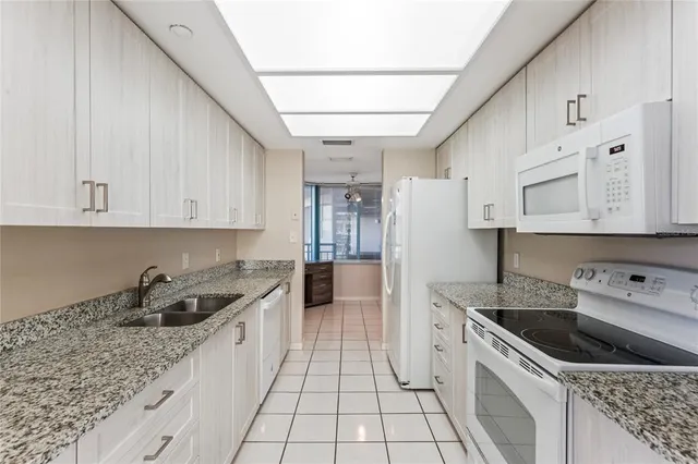 a kitchen with granite countertop a sink a stove and cabinets