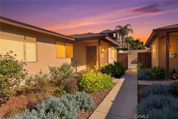 a yellow house with flower garden in front of it