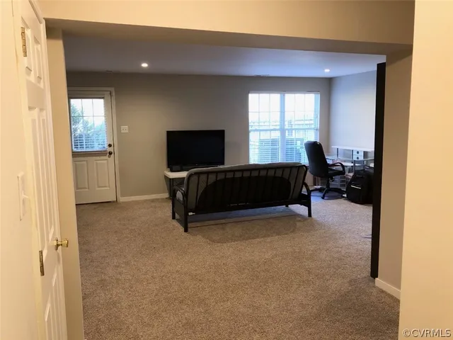a living room with furniture a flat screen tv and a window