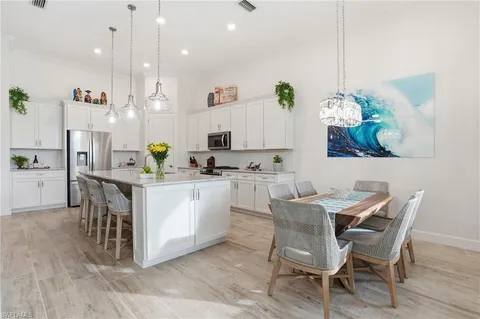 a dining room filled chandelier and kitchen view