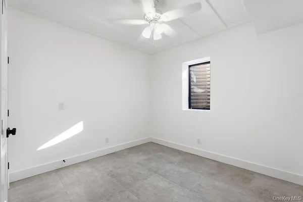 an empty room with a fan & a window