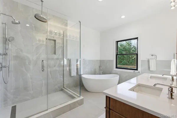 a bathroom with a tub sink mirror and a shower