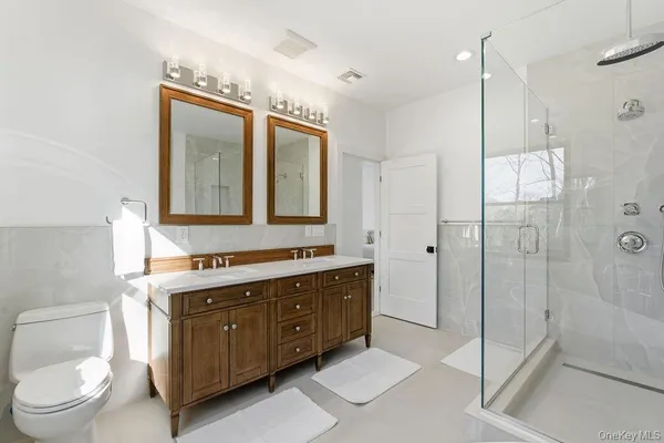 a spacious bathroom with a double vanity sink toilet and shower