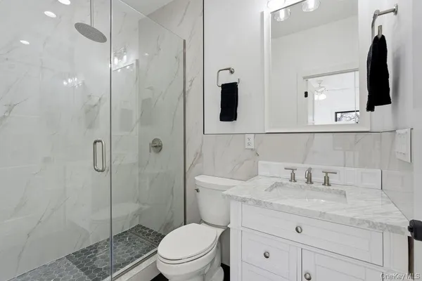 a bathroom with a granite countertop sink a toilet a mirror and shower