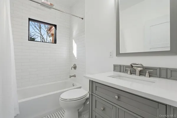 a bathroom with a granite countertop toilet a sink a mirror and a bathtub