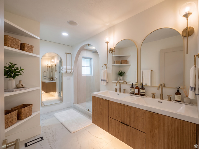 1860 Spring Lane Holladay, UT 84117 - Photo 12 of 32 Dual arched mirrors and sconces, wood-finish floating vanity with dual sinks, built-in shelving, and marble-finish flooring