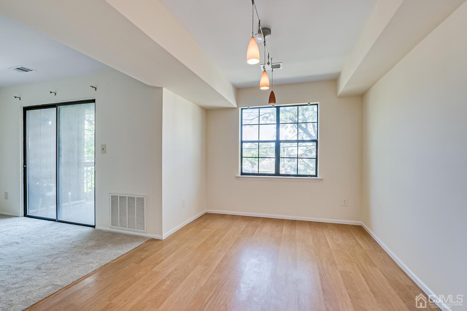 116 Keystone Court, Unit 1162 Woodbridge, NJ 07095 - Photo 11 of 28 an empty room with wooden floor chandelier and windows