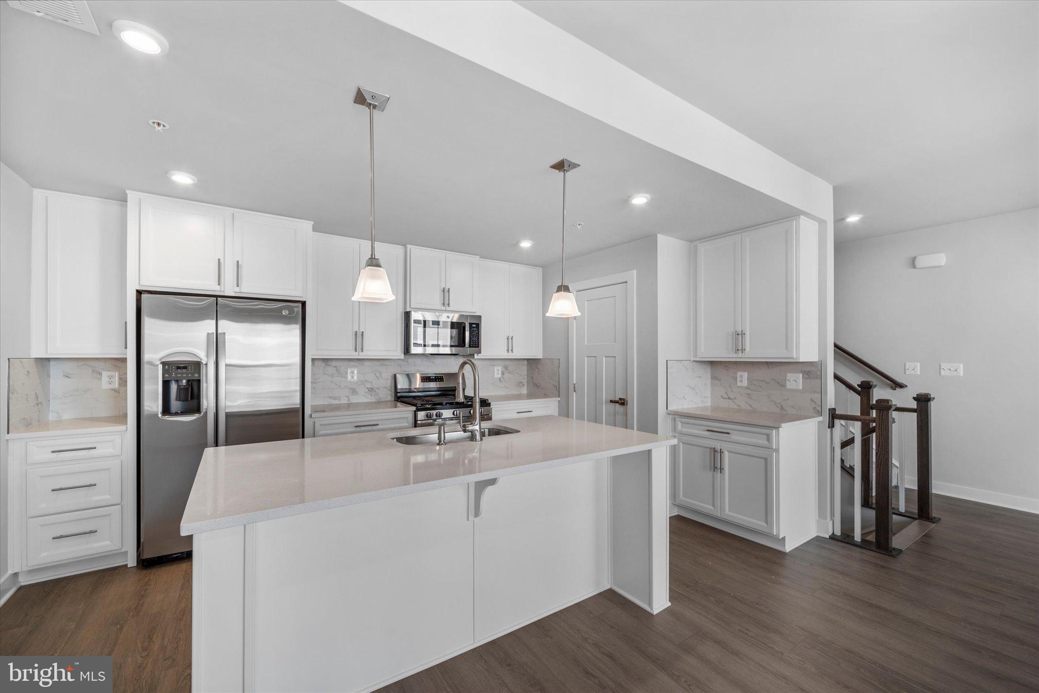 42530 Invergordon Terrace Sterling, VA 20166 - Photo 8 of 39 a kitchen with stainless steel appliances kitchen island granite countertop a refrigerator a sink dishwasher a stove and white cabinets with wooden floor