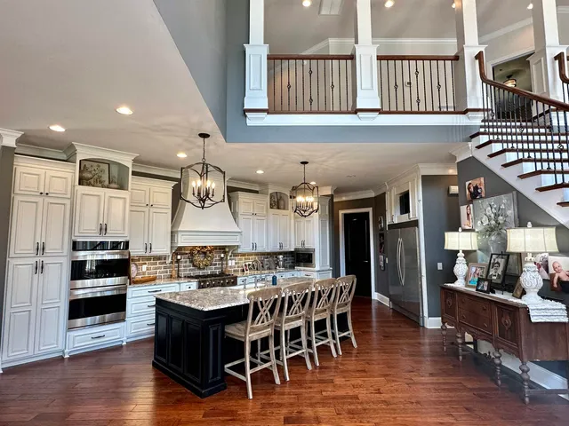 a kitchen with stainless steel appliances granite countertop a sink dishwasher a dining table and chairs with wooden floor