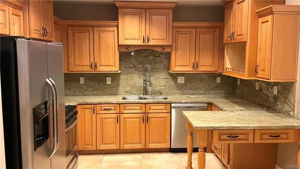 a kitchen with granite countertop wooden cabinets and a refrigerator