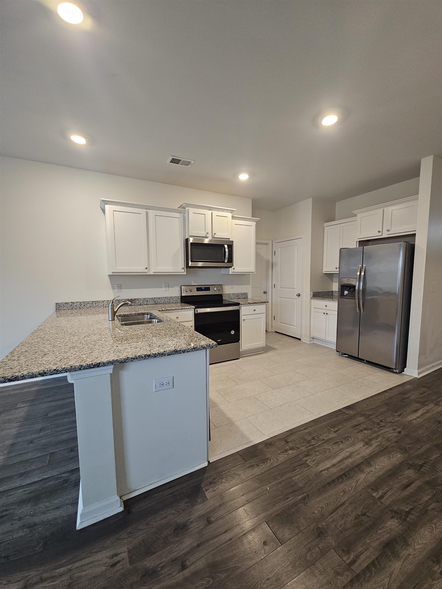 304 Forestbrook Cove Circle Myrtle Beach, SC 29588 - Photo 4 of 8 Kitchen featuring white cabinetry, stainless steel appliances, light stone countertops, light wood finished floors, and breakfast bar.