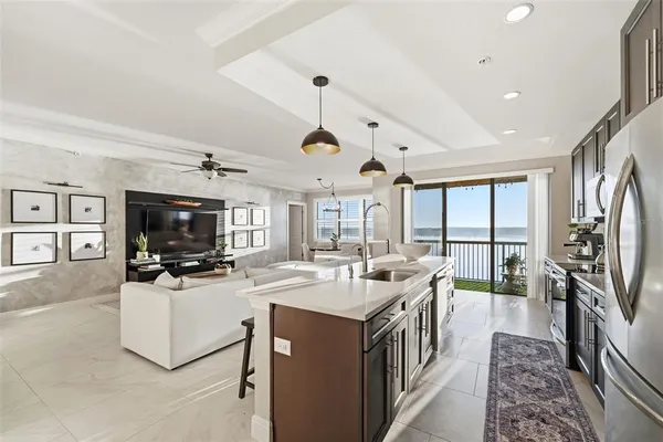 a kitchen with stainless steel appliances granite countertop a sink a stove a refrigerator and island with wooden floor