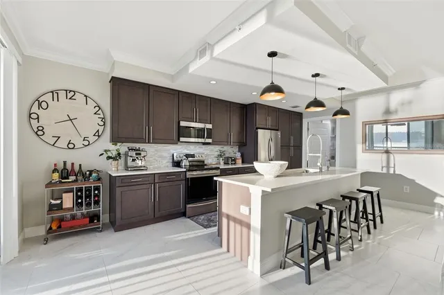 a kitchen with stainless steel appliances granite countertop a sink a stove a refrigerator and island with wooden floor
