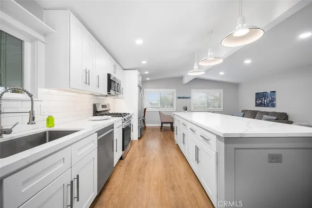 a large kitchen with stainless steel appliances lots of white cabinets and white appliances