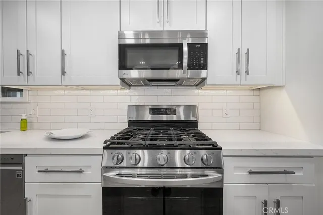 a kitchen with granite countertop stainless steel appliances and white cabinets