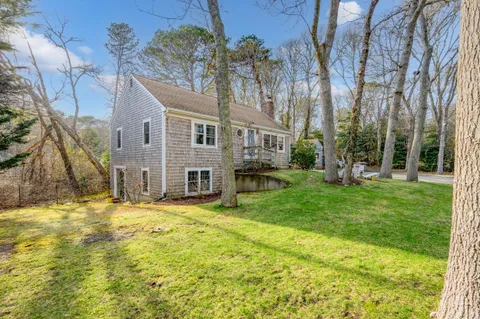 a view of a house with a big yard and large tree