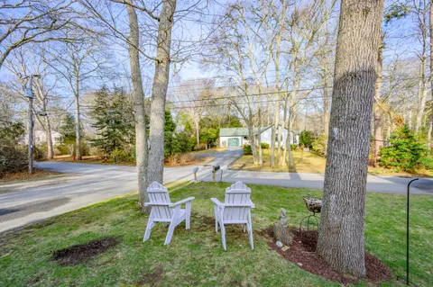 a view of a house with a yard and large trees