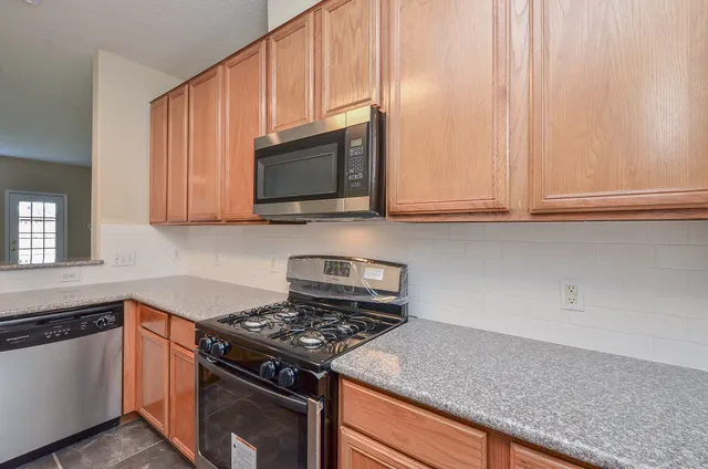 a kitchen with stainless steel appliances granite countertop white cabinets and a stove top oven