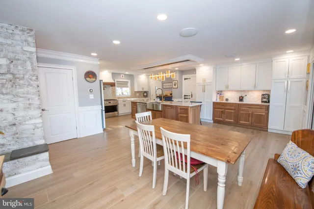 a living room with stainless steel appliances furniture a rug and a kitchen view