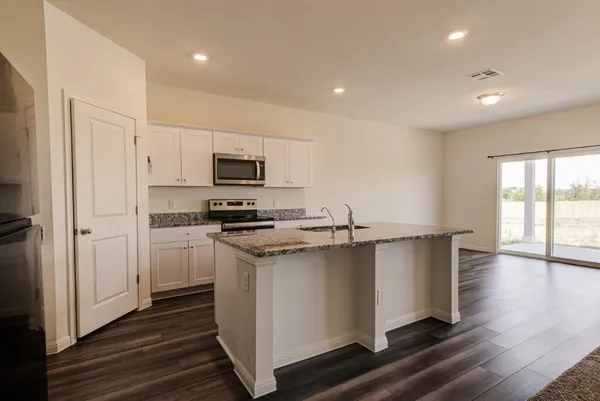 a view of kitchen with kitchen island stainless steel appliances refrigerator sink and cabinets