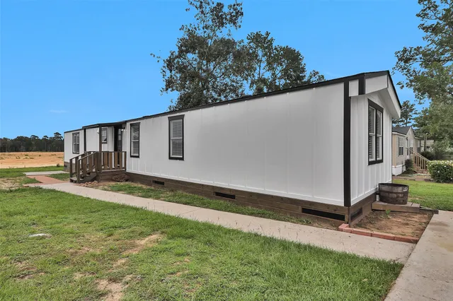 a backyard of a house with lawn chairs plants and large tree