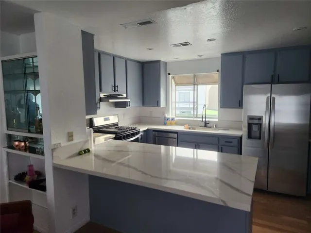 a kitchen with kitchen island granite countertop a sink refrigerator and microwave