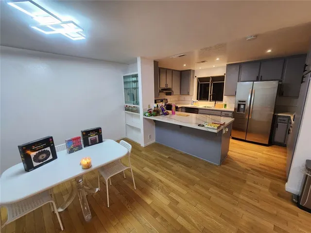 a kitchen with stainless steel appliances a dining table chairs refrigerator and sink