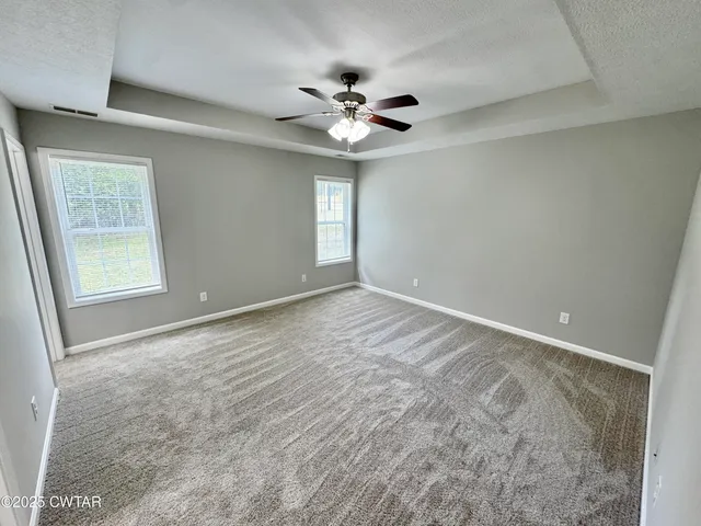 a view of an empty room with a chandelier fan