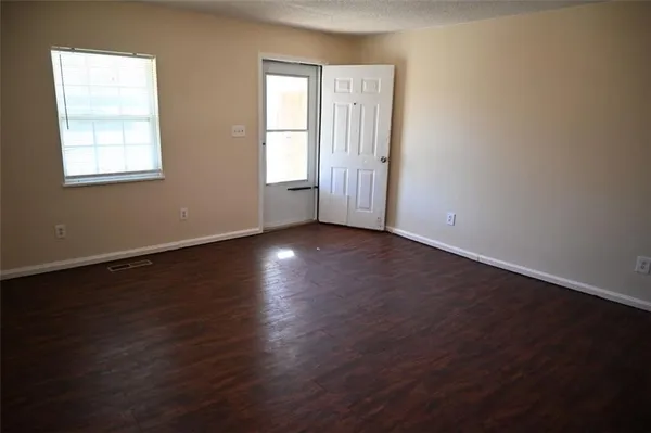 a view of an empty room with wooden floor and a window