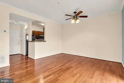 a view of empty room with wooden floor and ceiling fan