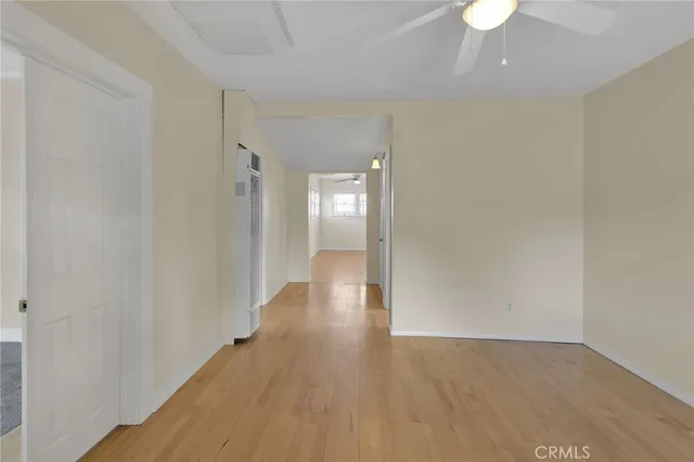 a view of a hallway with wooden floor and a refrigerator