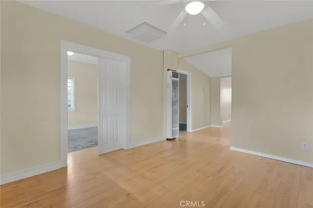 a view of an empty room with wooden floor and a chandelier fan