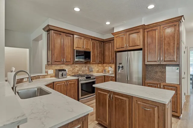 a kitchen with stainless steel appliances granite countertop a sink a stove a refrigerator cabinets and a microwave