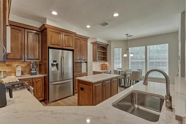 a kitchen with stainless steel appliances granite countertop a refrigerator a sink a stove and a refrigerator