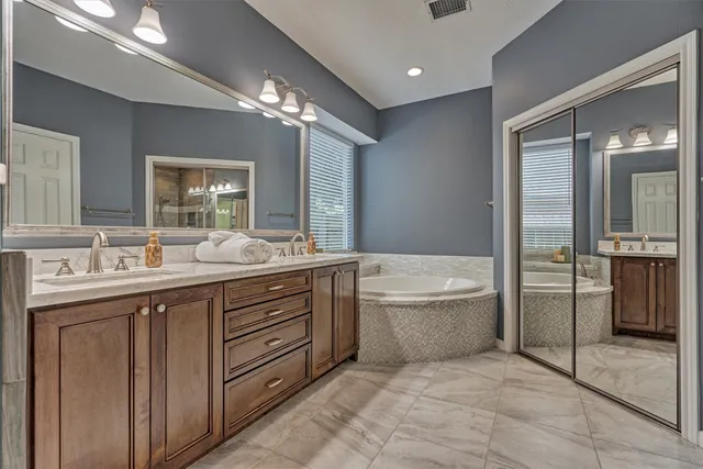 a bathroom with a granite countertop sink a large mirror and a bathtub