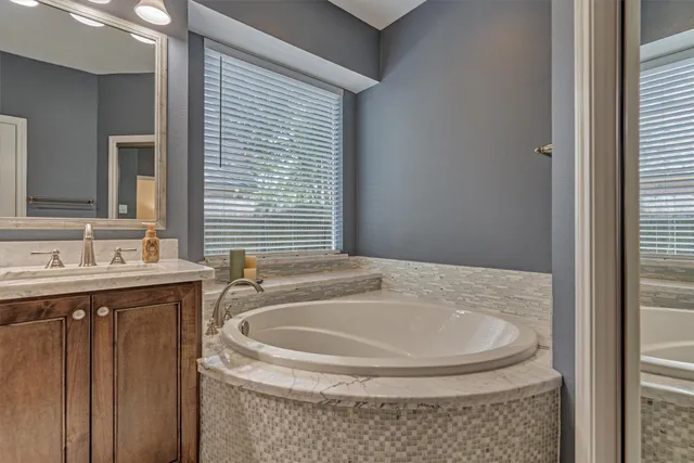a bathroom with a granite countertop sink and a bathtub
