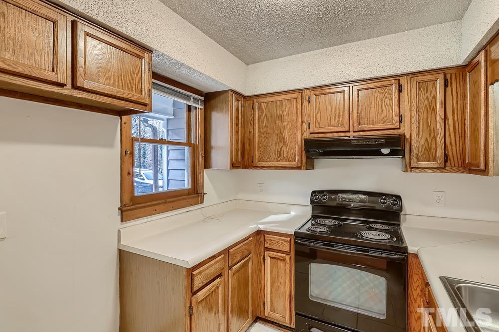 5604 Thea Lane, Unit B Raleigh, NC 27606 - Photo 11 of 27 a kitchen with stainless steel appliances granite countertop a stove a sink and a microwave