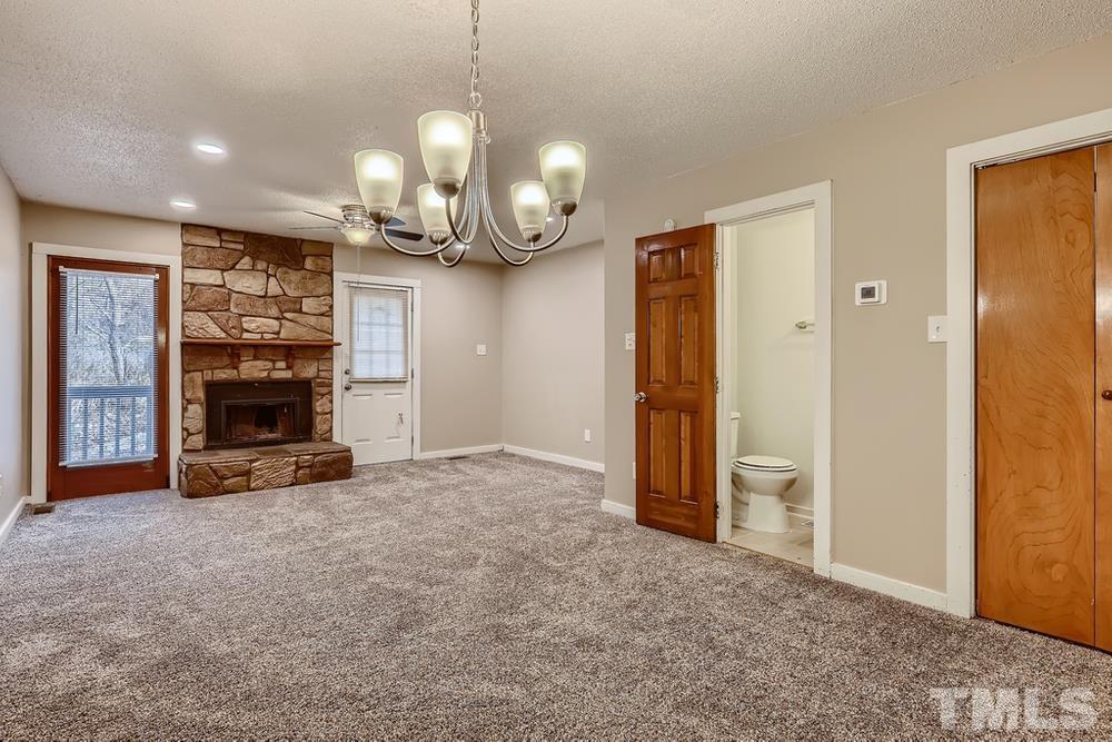 5604 Thea Lane, Unit B Raleigh, NC 27606 - Photo 16 of 27 an empty room with a fireplace and chandelier fan