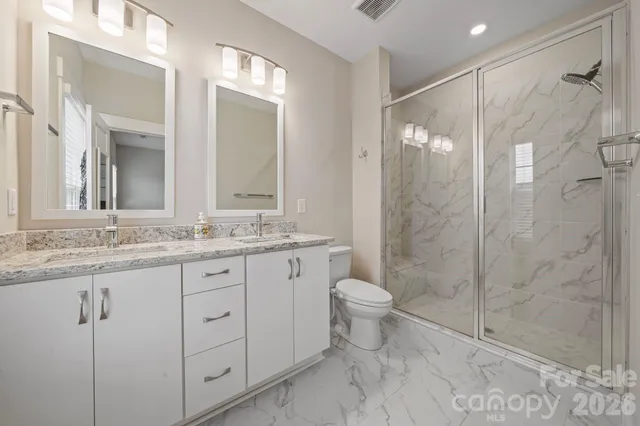a bathroom with a granite countertop sink toilet a mirror a vanity and shower