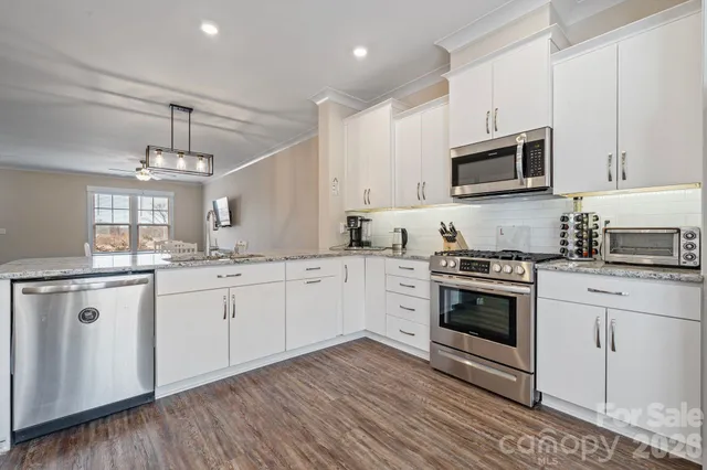 a kitchen with stainless steel appliances granite countertop a stove a sink and a microwave