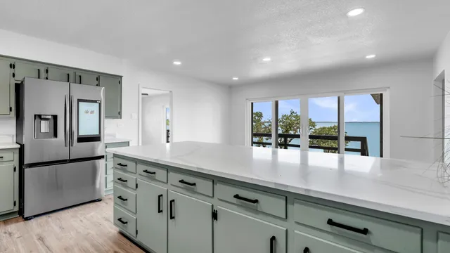 a kitchen with stainless steel appliances granite countertop a refrigerator a sink and white cabinets
