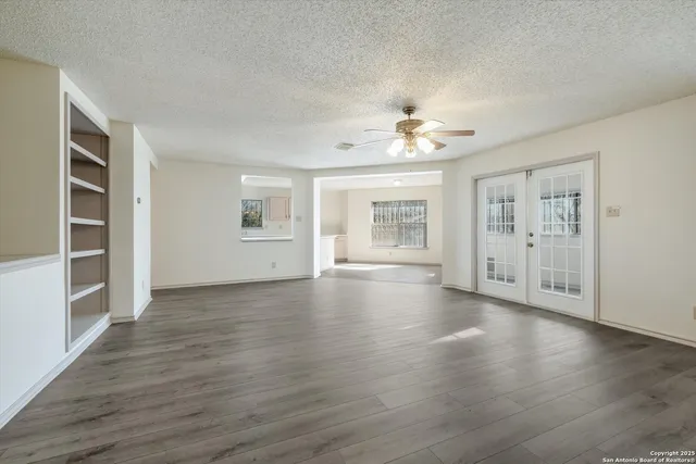 a view of an empty room with a window and wooden floor