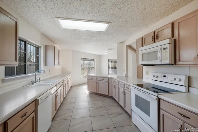 a large white kitchen with stainless steel appliances granite countertop a lot of counter space and a sink