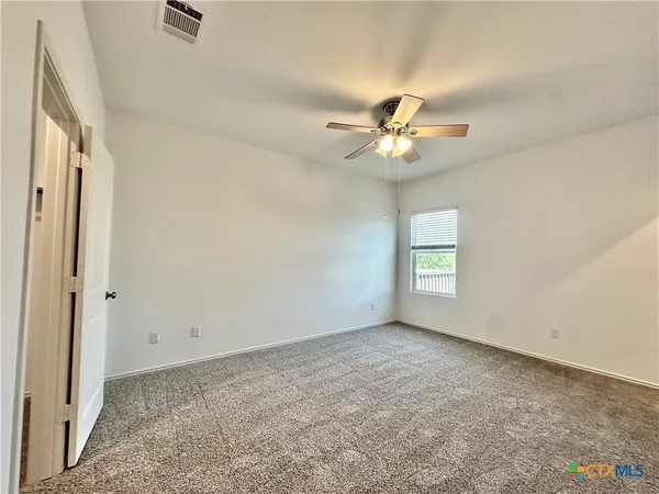 an empty room with a chandelier fan and windows