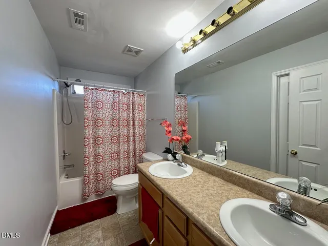 a bathroom with a granite countertop double vanity sink toilet and shower